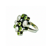 Load image into Gallery viewer, Gold ring with green gemstones on a light fabric background