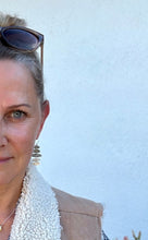 Load image into Gallery viewer, Woman wearing a beige coat with a white scarf against a light blue background