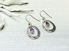 Load image into Gallery viewer, Silver earrings with purple gemstones on a white fabric background