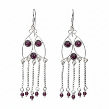 Load image into Gallery viewer, Silver earrings with red gemstones on a light gray background with green leaves.